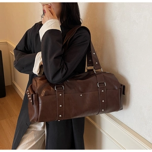 Detail of vintage dark brown travel bag with silver studs and metal ring hardware