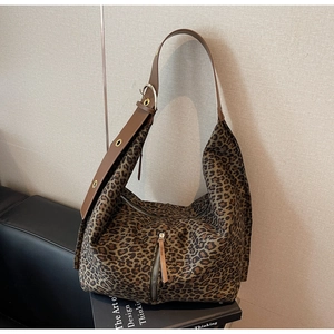 Détail de sac en daim léopard avec large bandoulière en cuir et œillets dorés