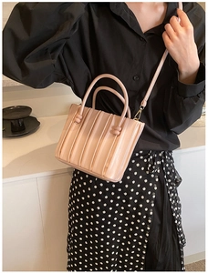 Detail of light beige pleated bucket bag featuring elegant folds and gold metal hardware