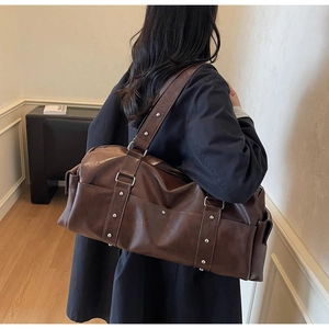 Detailed back view of a brown vintage leather travel bag with metal stud decorations