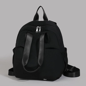 Detail of black waterproof nylon backpack with silver zippers and elastic side pockets