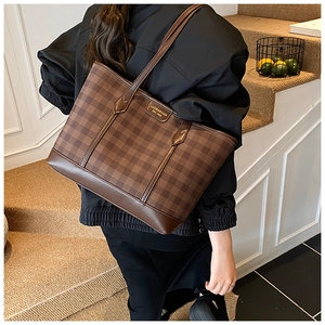 Close-up of brown checkered tote bag featuring a leather strap and vintage brand label