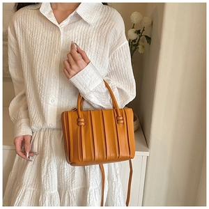 Detailed view of yellow pleated soft leather handbag with unique spherical decorative accents