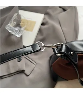 Detail of silver metal hook and black leather strap on a textured dumpling bag