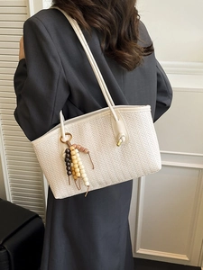 Women white woven tote bag with wooden bead tassels shown on shoulder over black blazer