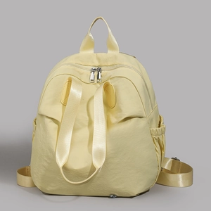 Detail of light yellow nylon backpack with silver zippers and side elastic pockets