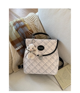 Close-up of beige plaid backpack with polka dots, silver metal clasp and plush bunny charm
