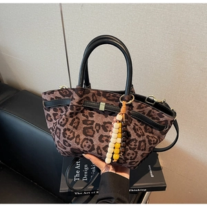 Detail of leopard print bucket bag with black leather handle and colorful beaded keychain