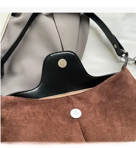 Detail of premium silver magnetic closure on a brown suede and black leather bag