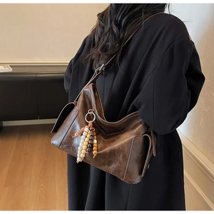 Detail of vintage brown leather crossbody bag with textured finish and tassel charm