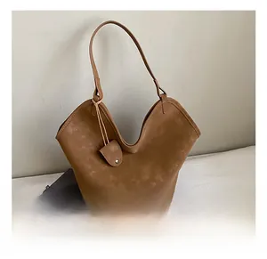 Detail view of brown faux suede tote bag with unique V-cut opening and small pouch