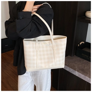 Detail view of large checkered tote bag showing strap and side profile on a model