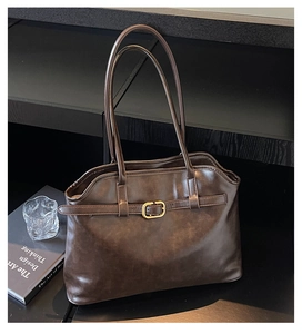 Détail du grand sac cabas en cuir marron foncé avec boucle dorée sur un bureau élégant