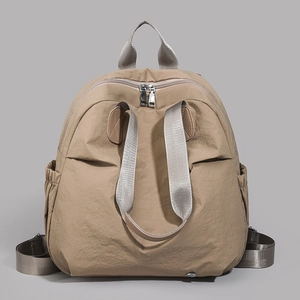 Detail of khaki nylon backpack showing wide straps, top handle and sturdy metal dual zippers