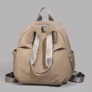 Detail of khaki nylon backpack featuring smooth silver dual zippers and elastic side pockets