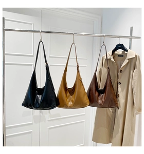 Minimalist large Hobo bags in black, caramel, and brown colors hanging on a rack