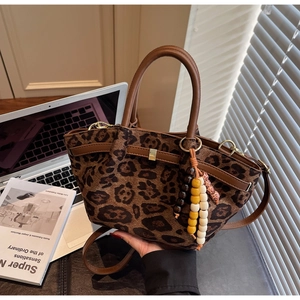 Detail of leopard print handbag with leather handle and colorful beaded charm accessory