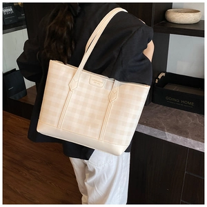 Detail of checkered shoulder tote bag with embossed brand logo on creamy leather finish