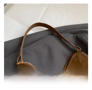 Close-up of retro brown shoulder bag showing smooth curved handle and fine stitching