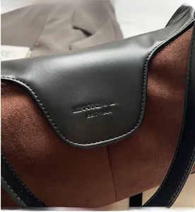 Close-up of suede and leather patchwork bag with embossed logo and fine stitching details