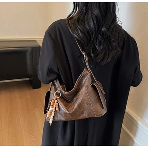 Detail of vintage brown leather bucket bag with wooden bead charm and side pocket