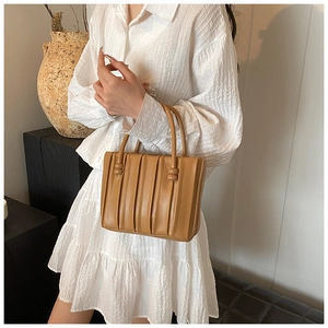 Detailed view of the vertical pleated texture on this light brown chic tote bag