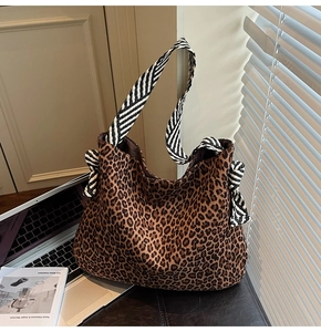 Détail du sac cabas léopard avec bandoulières rayées et nœuds décoratifs élégants