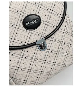 Detail of grid pattern backpack featuring silver metal twist lock and leather brand tag