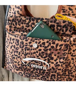Detail of leopard print tote bag featuring a front pocket with magnetic closure and logo