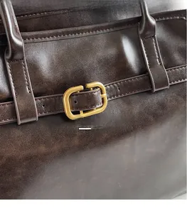 Détails de cuir marron foncé avec boucle dorée sur un sac à main fourre-tout chic