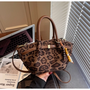 Detail of leopard print bucket bag with wooden bead charm and vintage leather straps