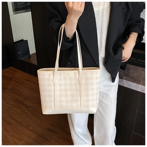 Detail of checkered tote bag with leather texture and brand tag on a professional model