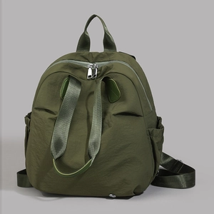Detail view of olive green nylon backpack with silver zippers and side pockets