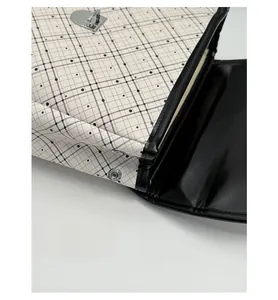 Detail of plaid fabric stitching with premium black leather and silver metal clasp