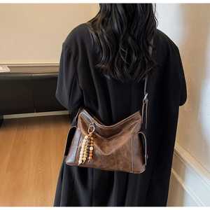Detail of vintage brown crossbody bag with retro leather texture and beaded charm