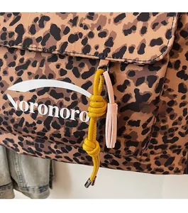 Detail of leopard print canvas bag featuring a pink tassel and yellow knot charm