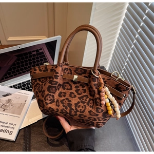Detail of leopard print tote bag featuring textured canvas, wood beads and leather handle