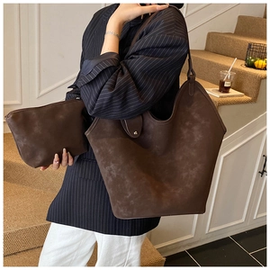 Detail of dark brown suede tote bag and matching pouch on a stone staircase