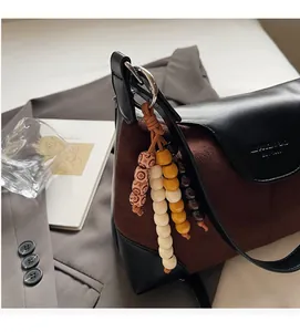 Detail of suede and leather shoulder bag with decorative colorful wooden bead tassels