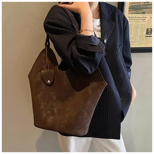 Detail of vintage brown suede tote bag with washed texture and metal buckle on side