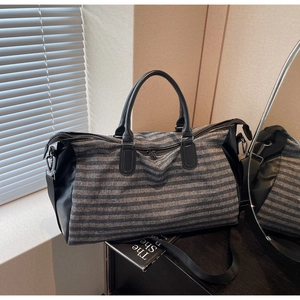 Detail of blue striped travel bag showing fabric texture, leather handles and zipper