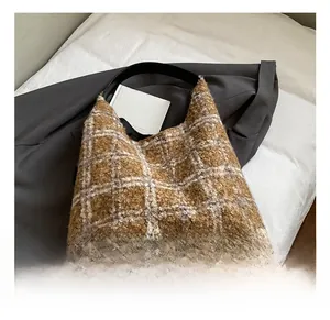 Détail du sac fourre-tout en laine à carreaux marron avec bandoulière noire sur tissu