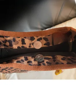 Detail of metal magnetic snap closure on a leopard print canvas tote bag