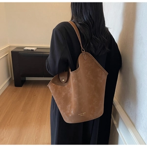 Braune Vintage-Wildleder-Einkaufstasche an der Schulter in minimalistischem Raum