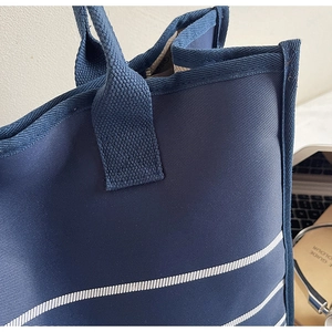 Detail view of high-density navy canvas tote bag with white stripes and zipper closure
