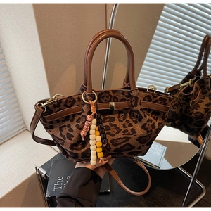 Close-up of leopard print handbag with leather straps and colorful beaded charm