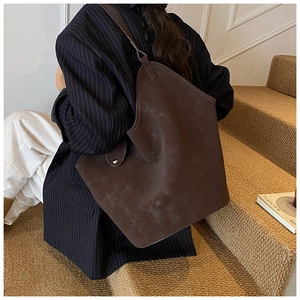 Model wearing dark coffee suede tote bag with asymmetric design and large capacity
