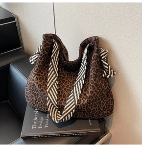 Détail du sac fourre-tout léopard avec poignées rayées noir et blanc sur fauteuil