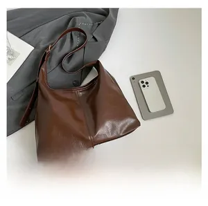 Detail of dark brown leather hobo bag with vertical stitching and long shoulder strap