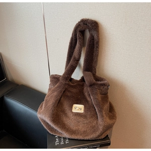 Détail d'un sac cabas en fausse fourrure marron café avec emblème doré de la lettre S